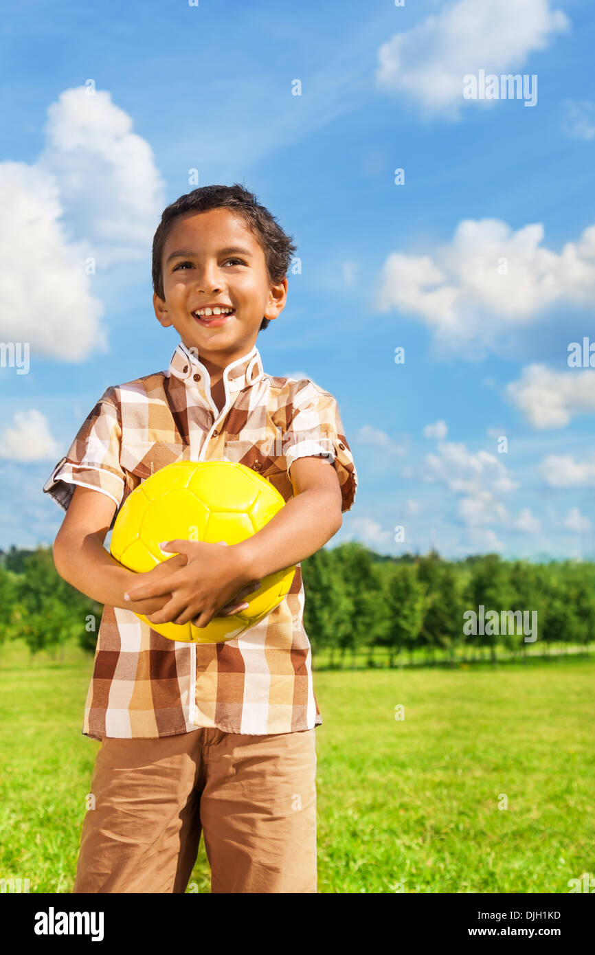 Beautiful happy smiling Asian boy holding yellow volleyball standing in the park Stock Photo