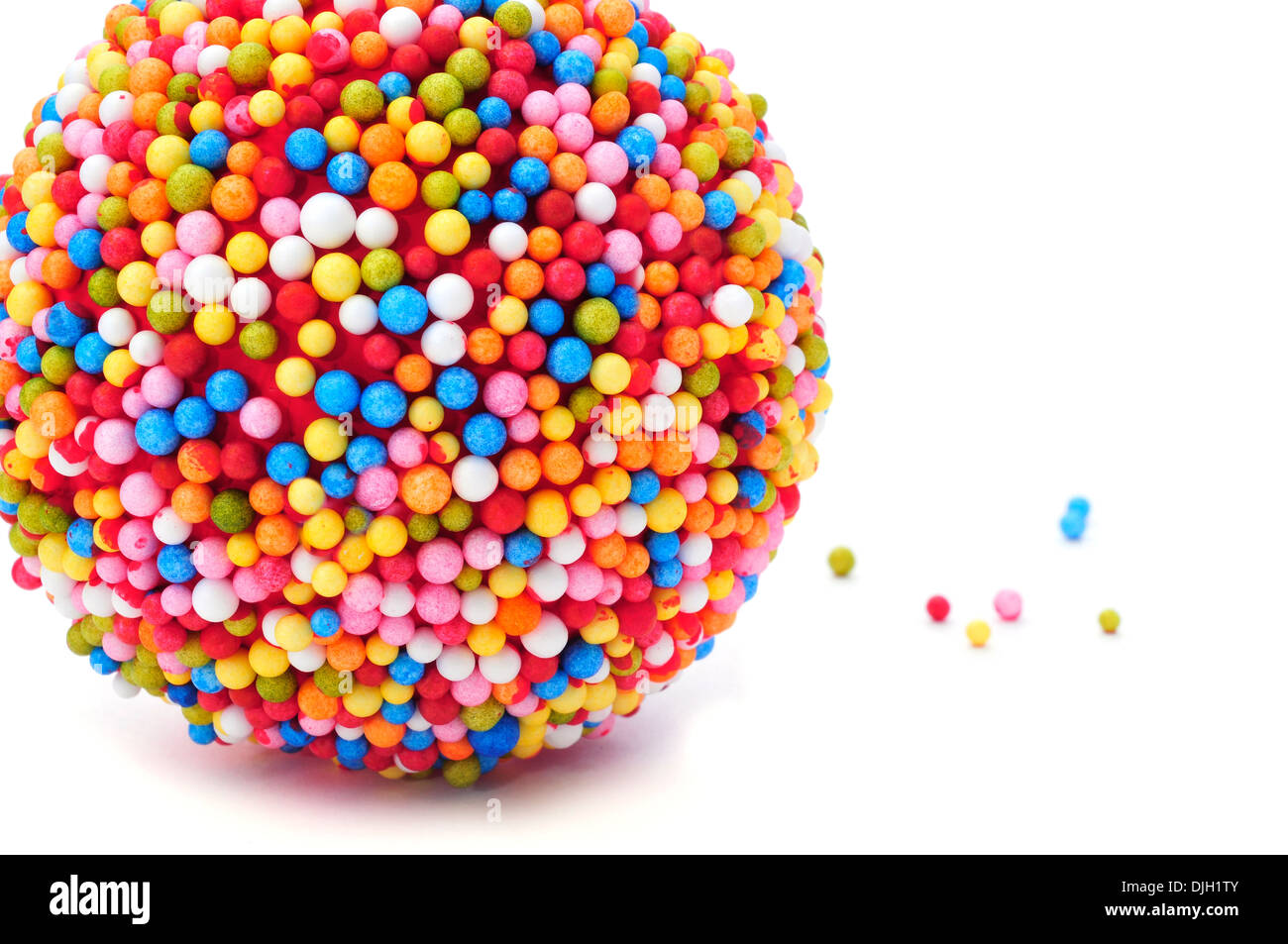 a ball coated with nonpareils of different colors on a white background ...