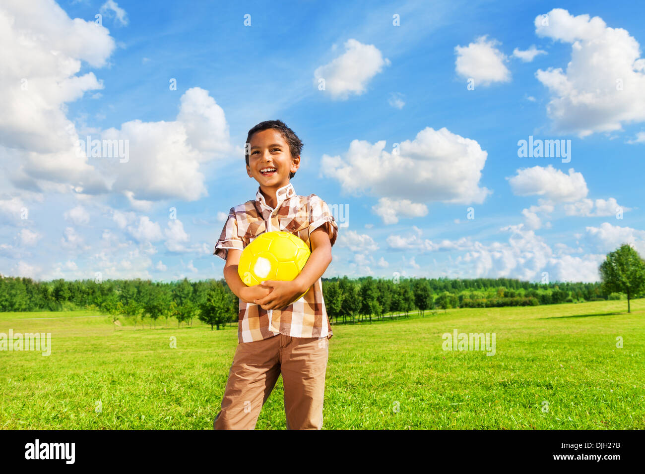 Happy dark boy standing with yellow volley ball Stock Photo