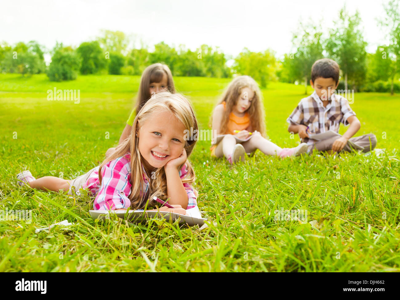 https://c8.alamy.com/comp/DJH662/cute-little-6-years-girl-drawing-in-park-outside-laying-on-the-grass-DJH662.jpg
