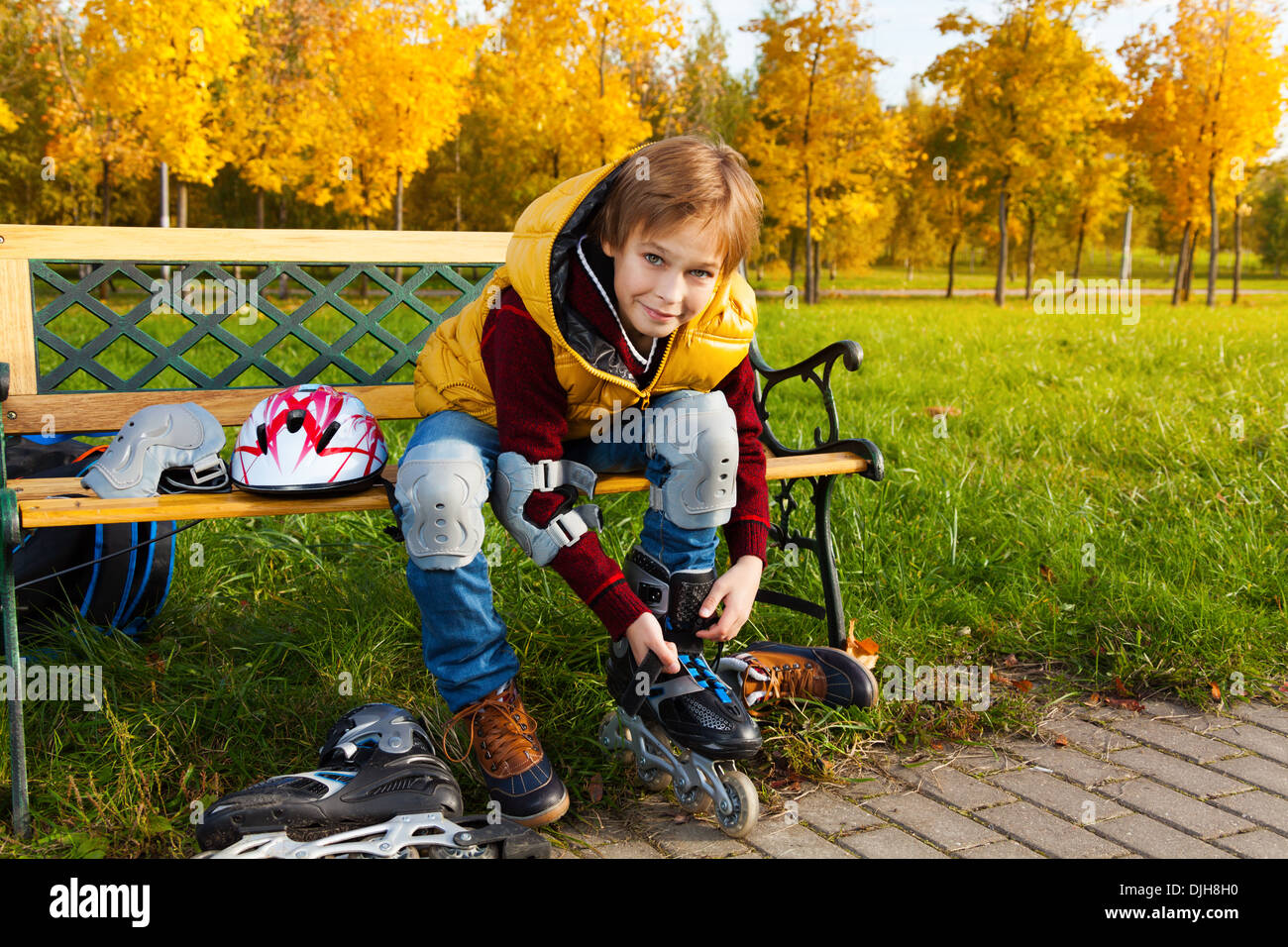 10 years old boy putting on roller blades sitting on the bench about to go skating Stock Photo