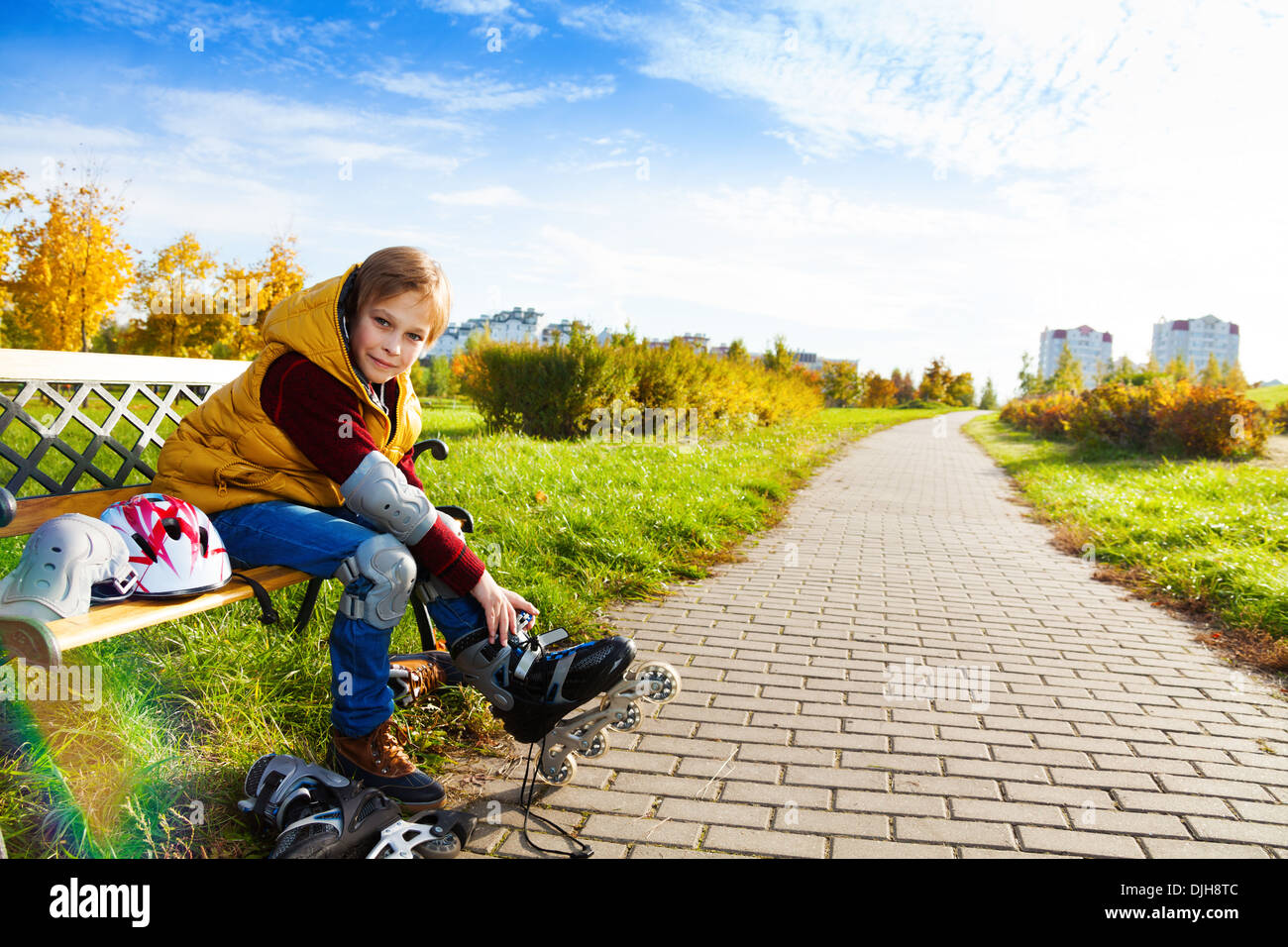 Portrait 10 years old boy putting on roller blades sitting on the bench about to go skating