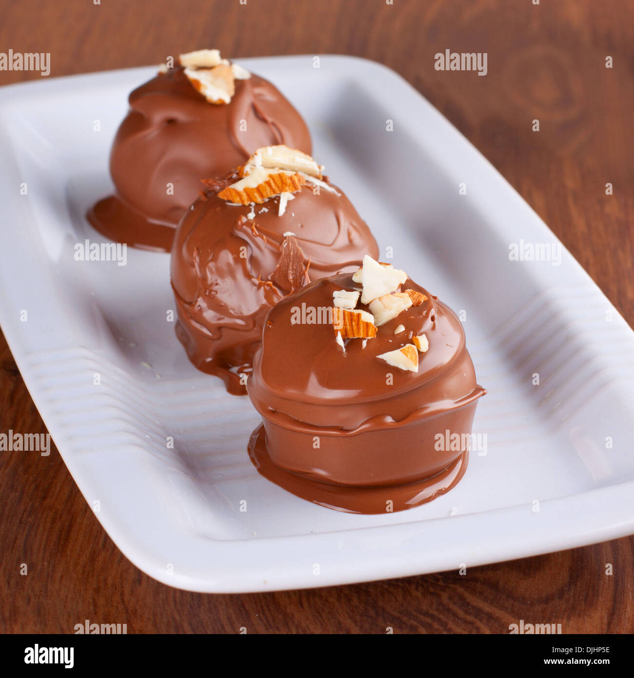 Three milk chocolate truffles decorated with almond crumbs Stock Photo