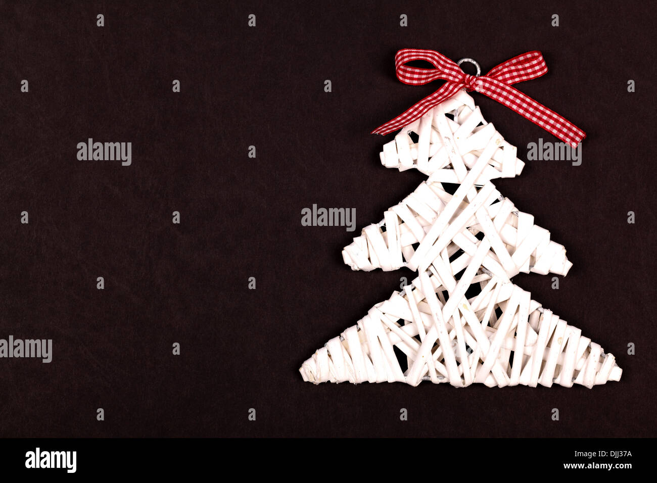 Little white Christmas tree with red ribbon over black background Stock