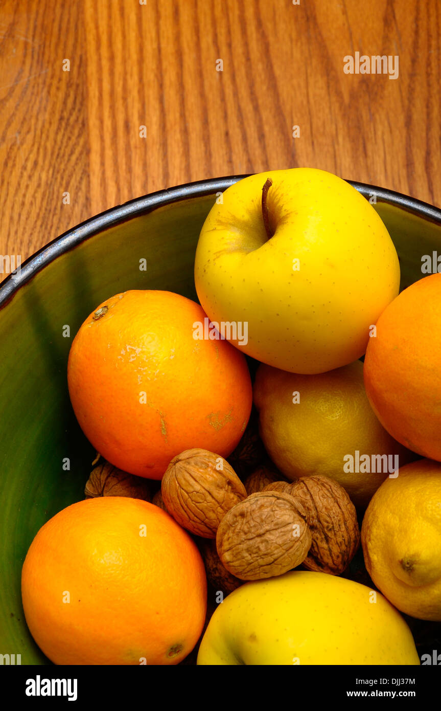 Some french winter fruits, apple, orange, nuts, lemon in a green bowl ...