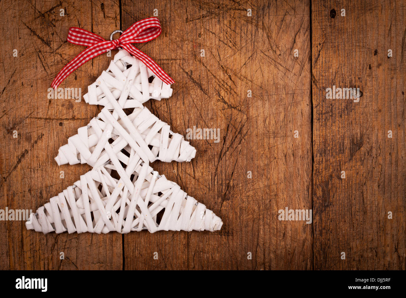 Little white Christmas tree with red ribbon over wooden background