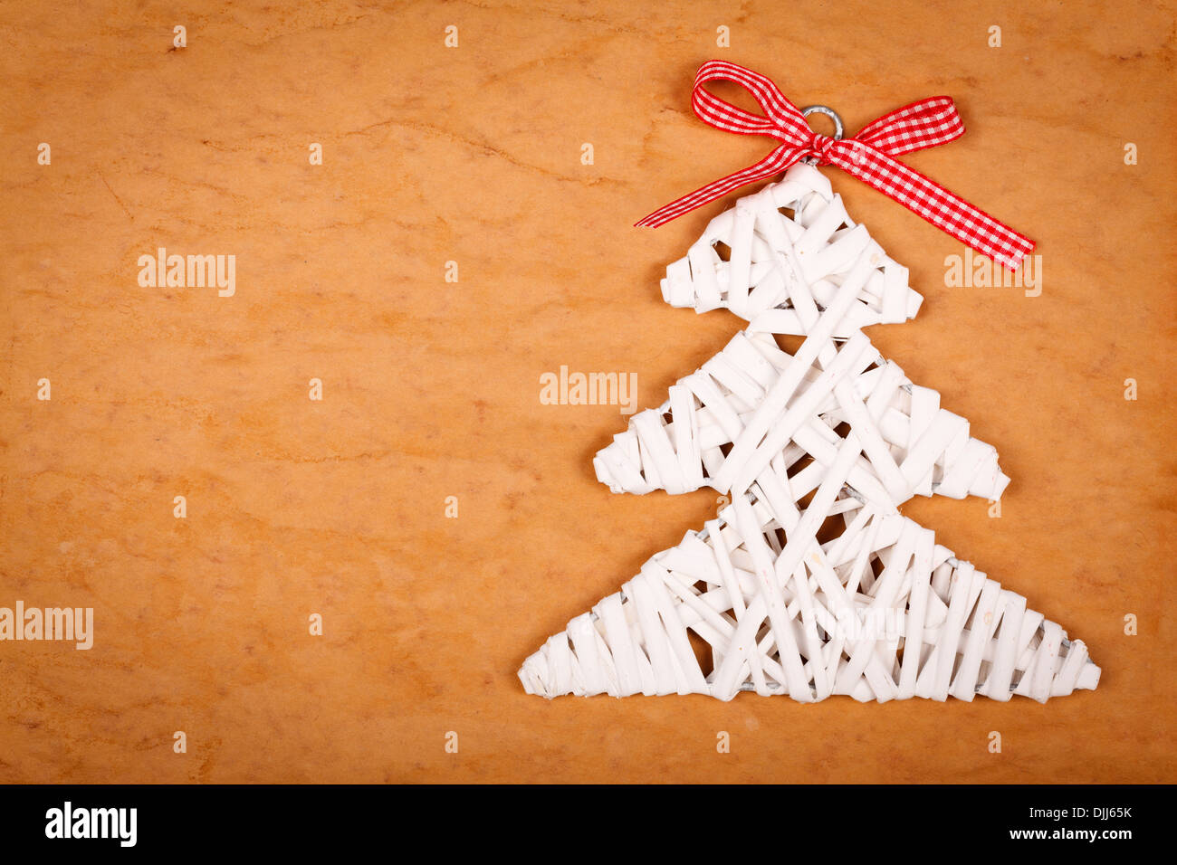 Little white Christmas tree with red ribbon over brown background Stock