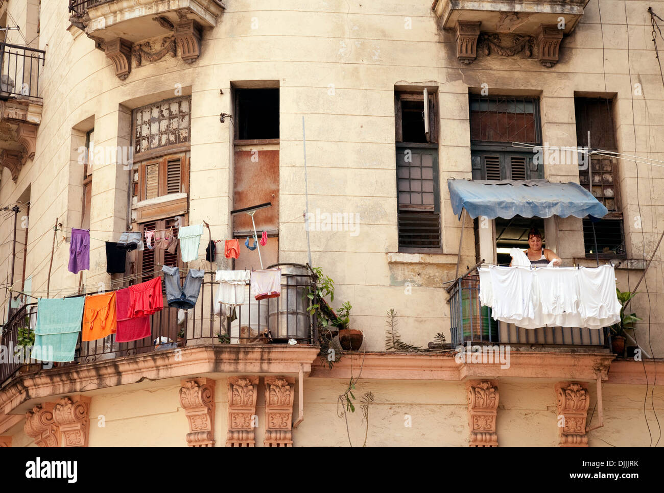 A woman hanging out her washing on a clothesline on her balcony
