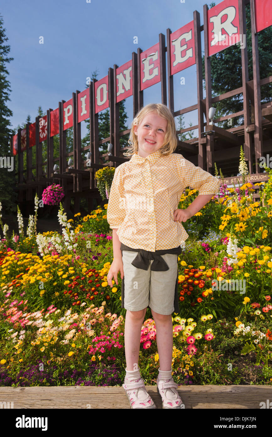 5 Year Old Caucasian Girl Standing In Front Of The Entrance To Pioneer Park Amusement Park, Summer, Fairbanks, Interior Alaska Stock Photo