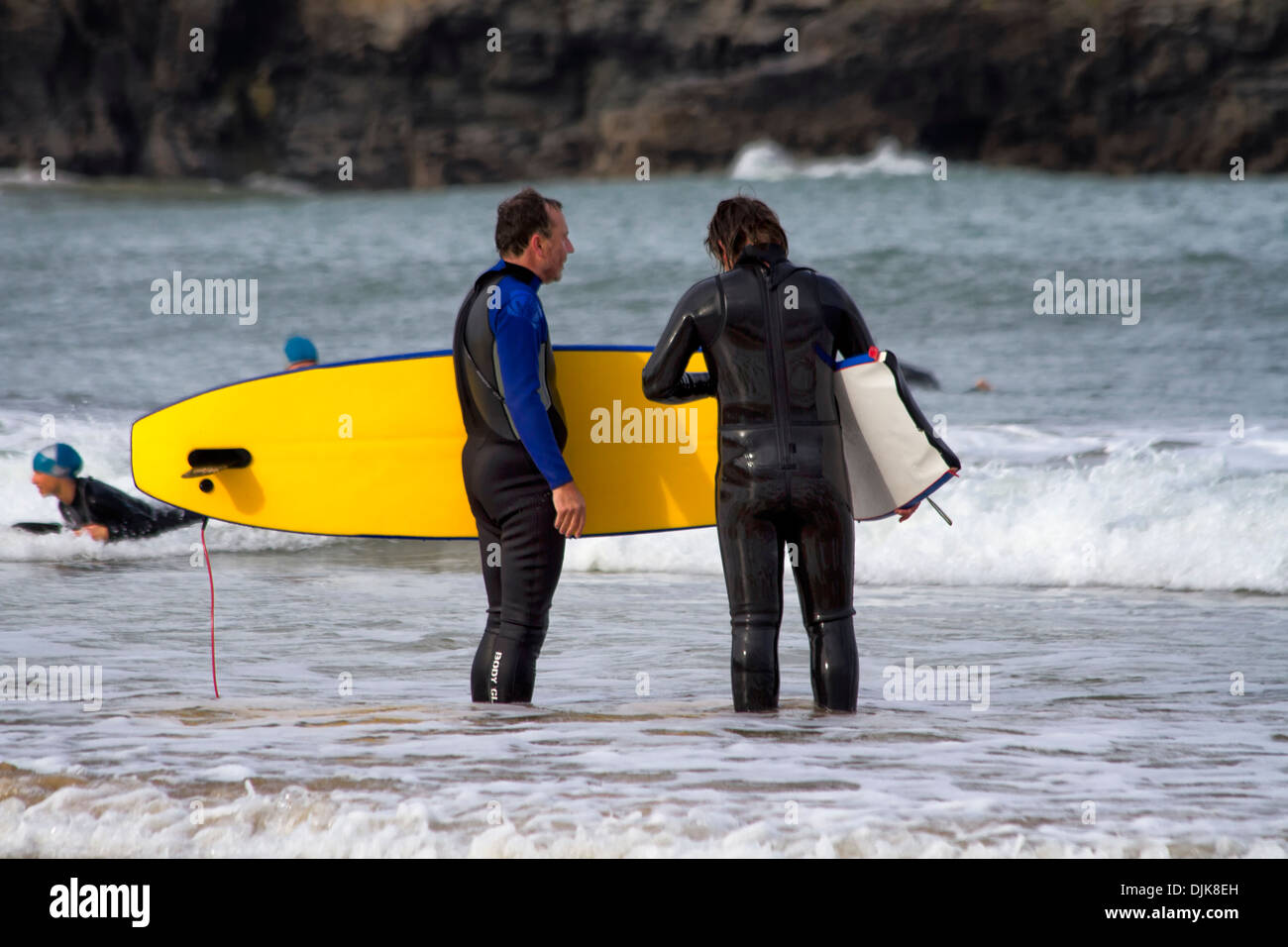 Two surfers with surfboards standing at the shoreline, Harlyn Bay, Cornwall, England Stock Photo