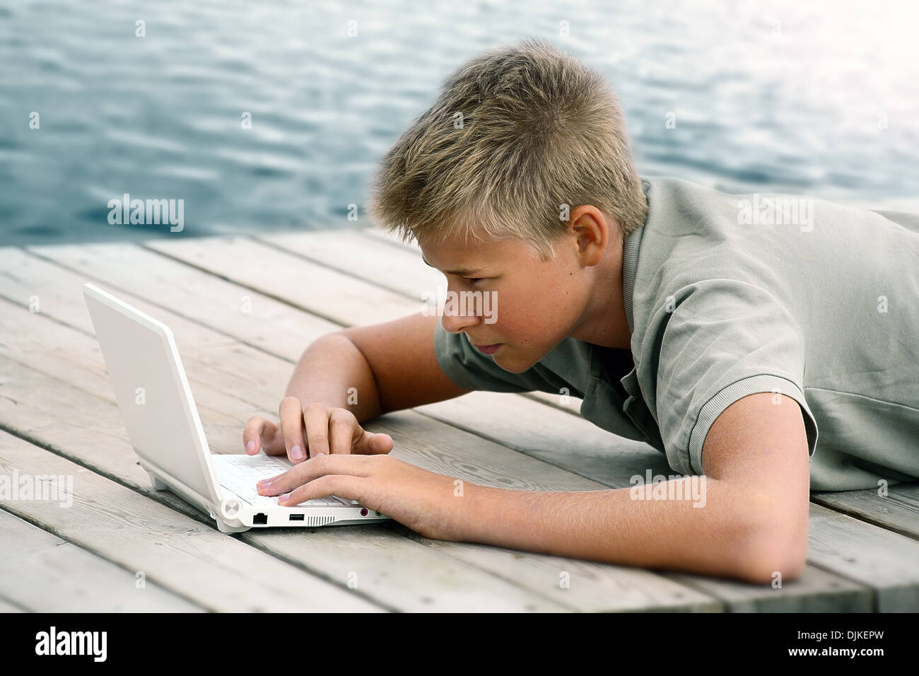 Boy writing with computer at the sea Stock Photo - Alamy