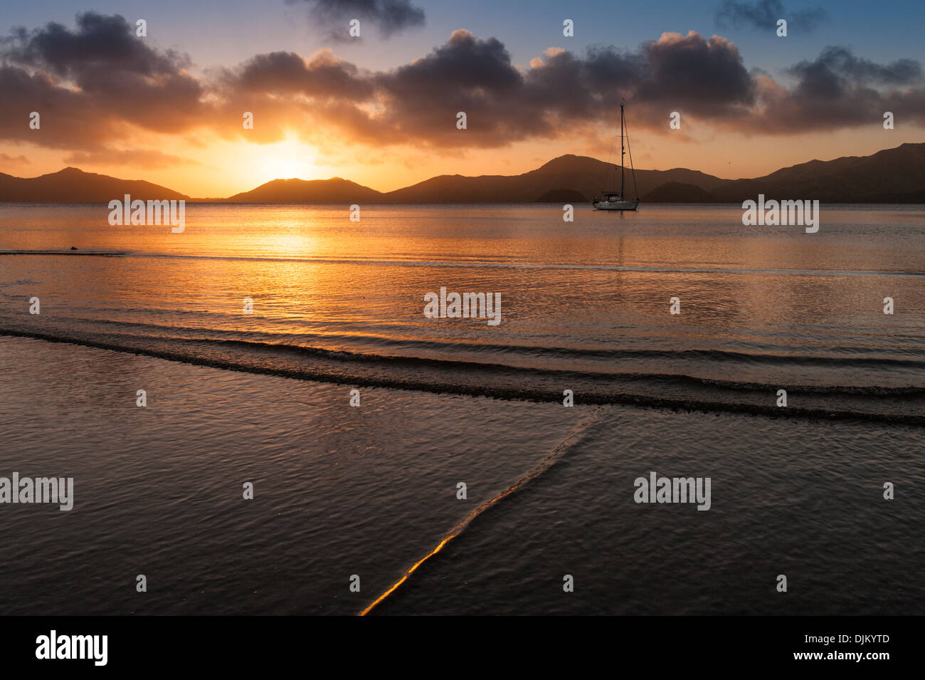 Sunset over the caldera at Totoya, with a cruising yacht at anchor off the village of Tovu. Totoya, southern Laus, Fiji. Stock Photo