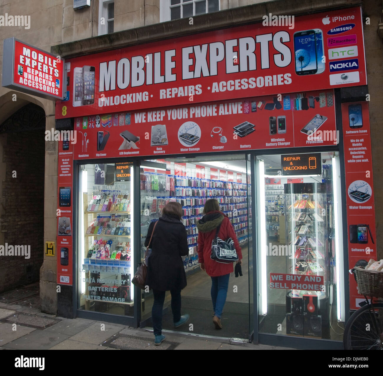 Two women entering Mobile Experts shop Cambridge England Stock Photo
