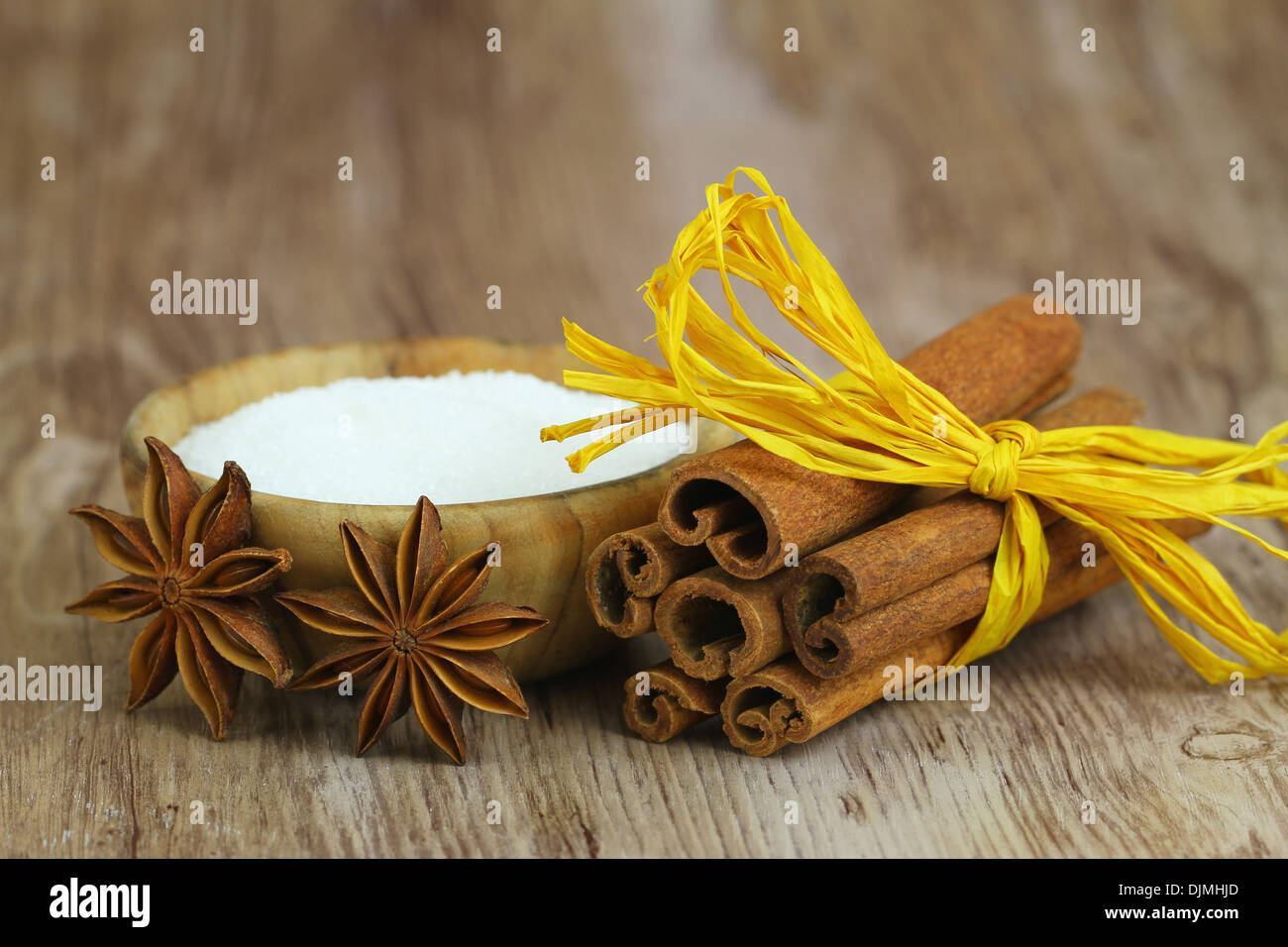 Star anise leaning against cinnamon sticks tied with yellow string ribbon  next to wooden sugar bowl Stock Photo - Alamy
