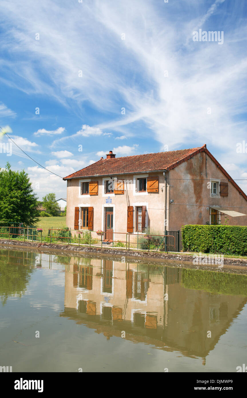 Lock keeper's cottage or house reflected in Canal du Centre Burgundy eastern France Stock Photo