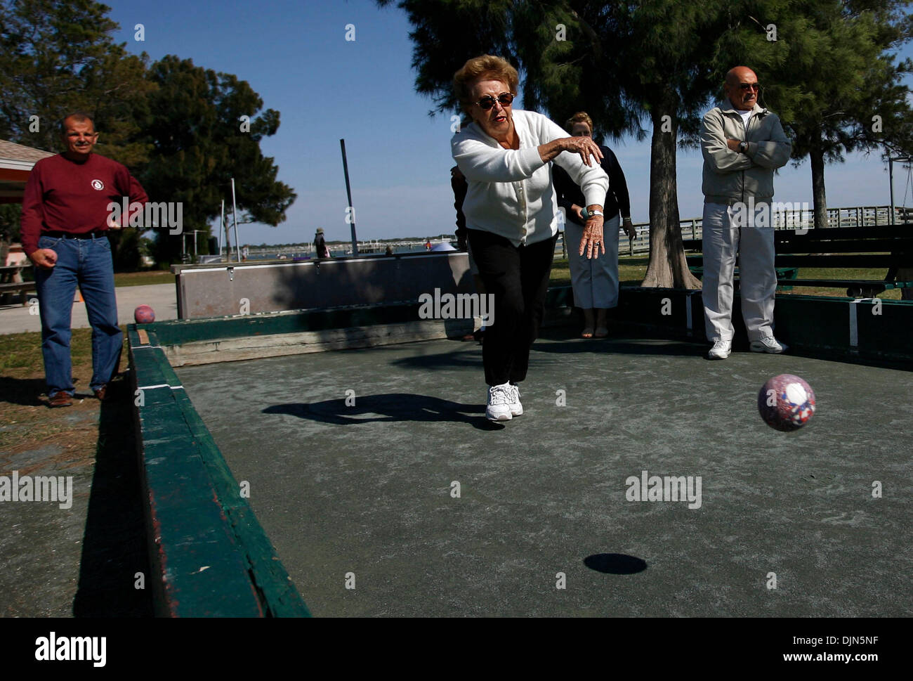 Mar 24, 2008 - St. Petersburg, Florida, USA - (Left to Right) Alberto Burk watches as a determined and competitive Virginia Cordano bowls as her husband and teammate Dr. Angel Cordano stands on the bocce ball courts at Gulfport Municipal Beach. The game was played with two three person teams which were composed of two veterans players per team and a husband and wife couple that are Stock Photo