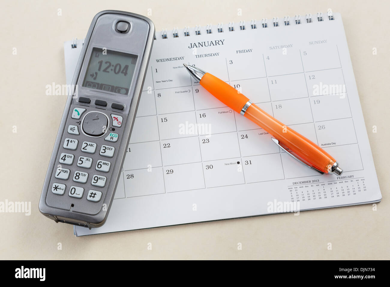 Cordless telephone handset with a pen pointing to New Years Day with new moon on a blank calendar page for January 2014 Stock Photo