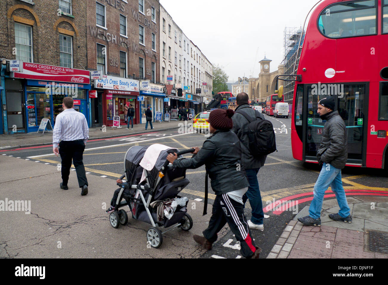 Pedestrians and mother pushing a pram crossing busy city street Grays Inn Road with buses cars traffic in King's Cross area of London UK  KATHY DEWITT Stock Photo