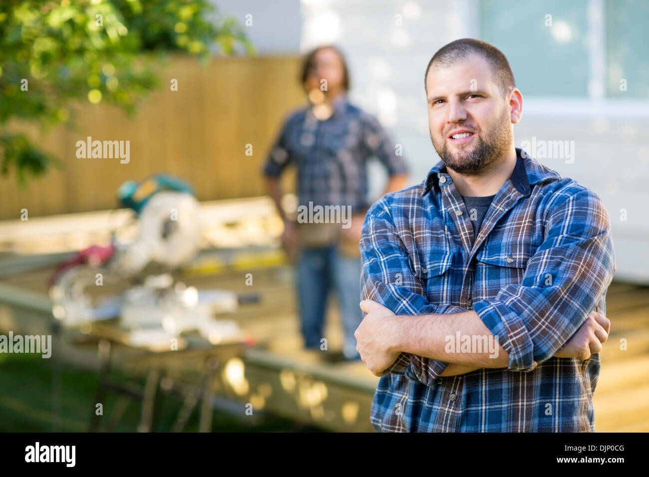 Confident Manual Worker With Hands Folded At Construction Site Stock Photo