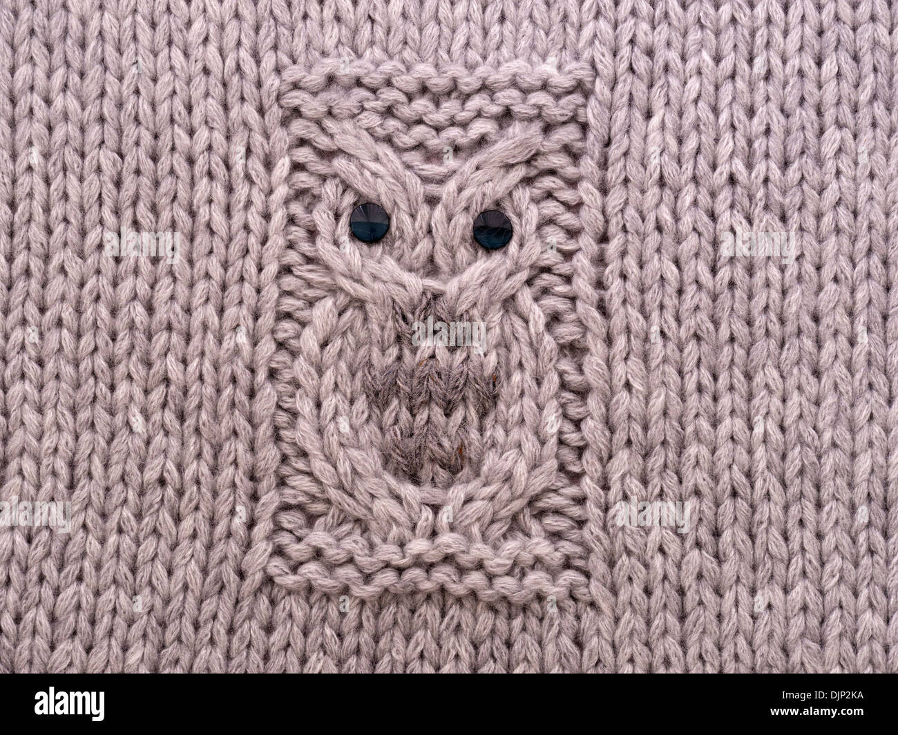 Hand knitted Owl motif pattern on cushion cover in grey wool. Stock Photo