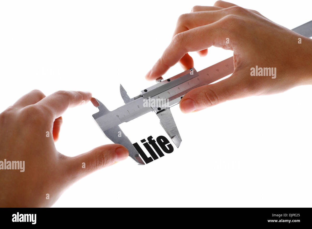 Two hands holding a caliper, measuring the word 'Life'. Stock Photo