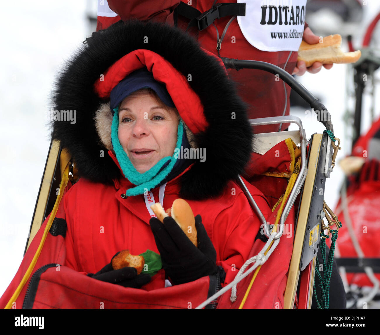 Mar 06, 2010 - Anchorage, Alaska, USA - Iditarider PATRICIA KENNEDY of Chicago winds up with a muffin and a hot dog at mile four where the trail runs adjacent to Wesleyan Drive during the Iditarod's ceremonial start Saturday morning. (Credit Image: © Erik Hill/Anchorage Daily News/ZUMA Press) Stock Photo