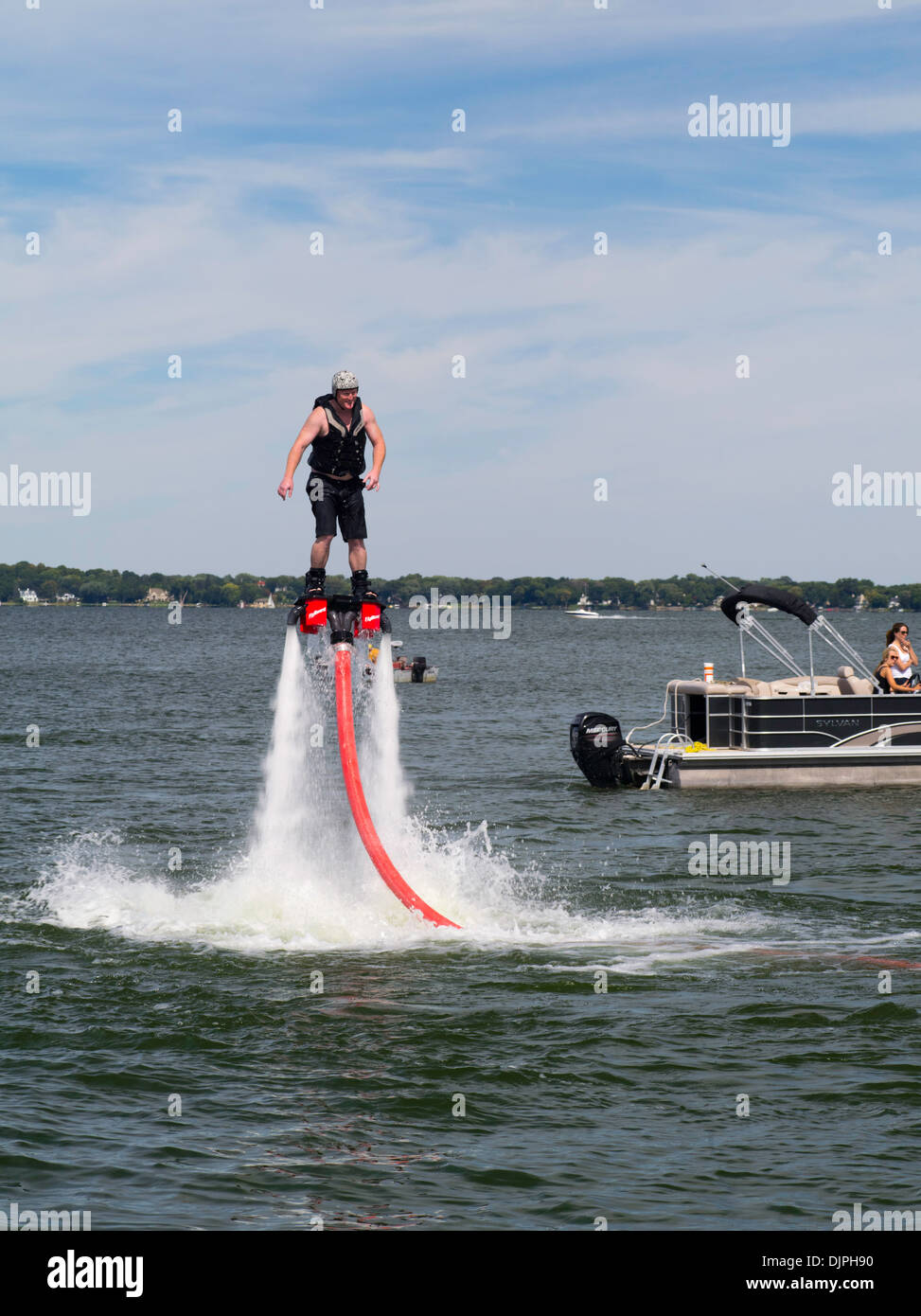 A man "flies" on a "fly board," with the help of a man on a jet ski