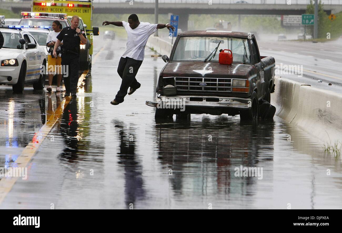 Apr. 24, 2010 - Memphis, Tn, U.S. - URBAN, SUBURBAN B1 CP LEAD w/e25weather - 24 april 10 (mwflip1) Photo by Mark Weber - Loard Cole (cq), middle, jumps into standing water as he surveys the damage to his truck after heavy winds and rain caused it to fish tale then flipping it onto its roof  while traveling on I-240 east just east of Perkins. Cole was riding with his five month pre Stock Photo