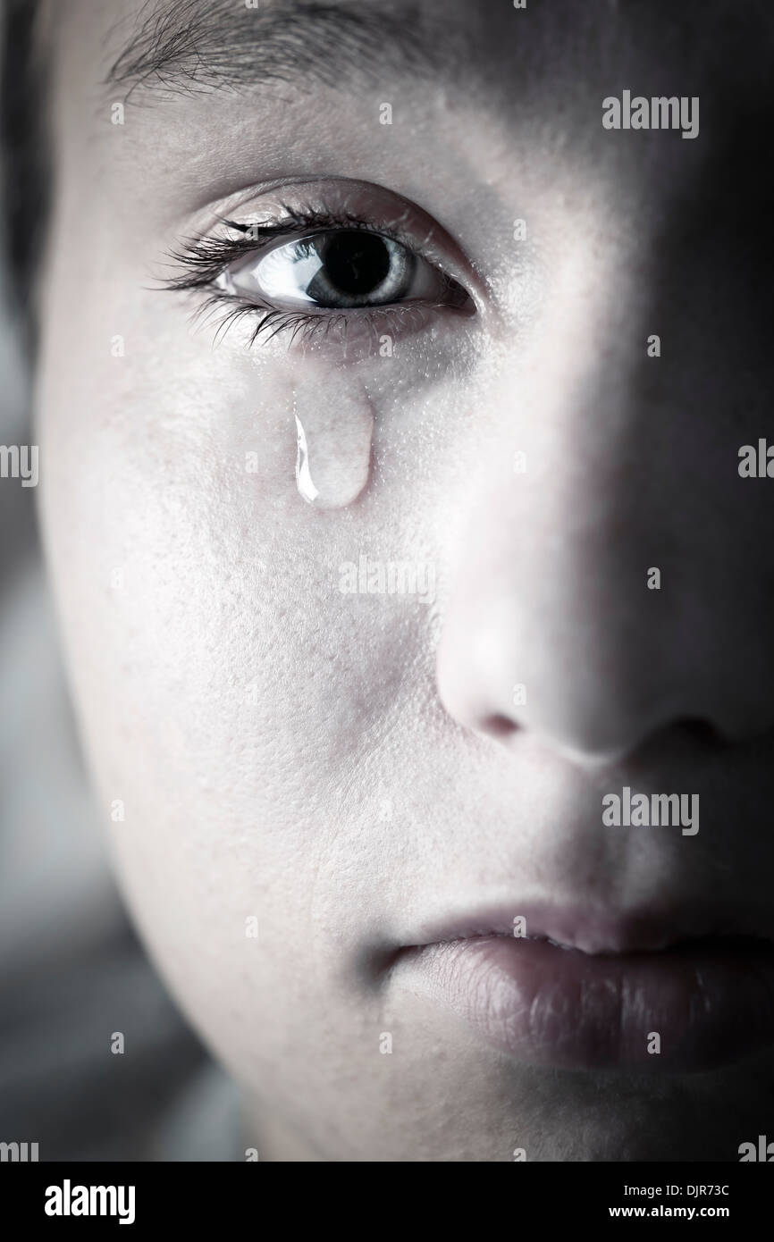 Closeup on face of crying girl with tear rolling down cheek Stock Photo