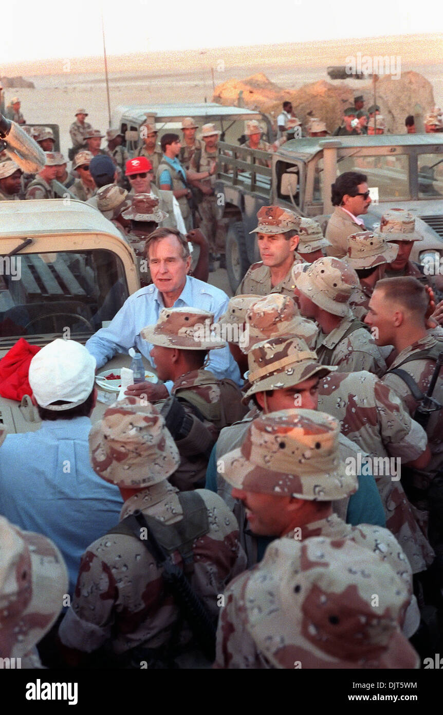 US President George Bush leans on the hood of a Humvee as he talks to Marines during a Thanksgiving Day visit to a desert encampment November 22, 1990 in Saudi Arabia. The President is visiting U.S. troops in Saudi Arabia for Operation Desert Shield. Stock Photo