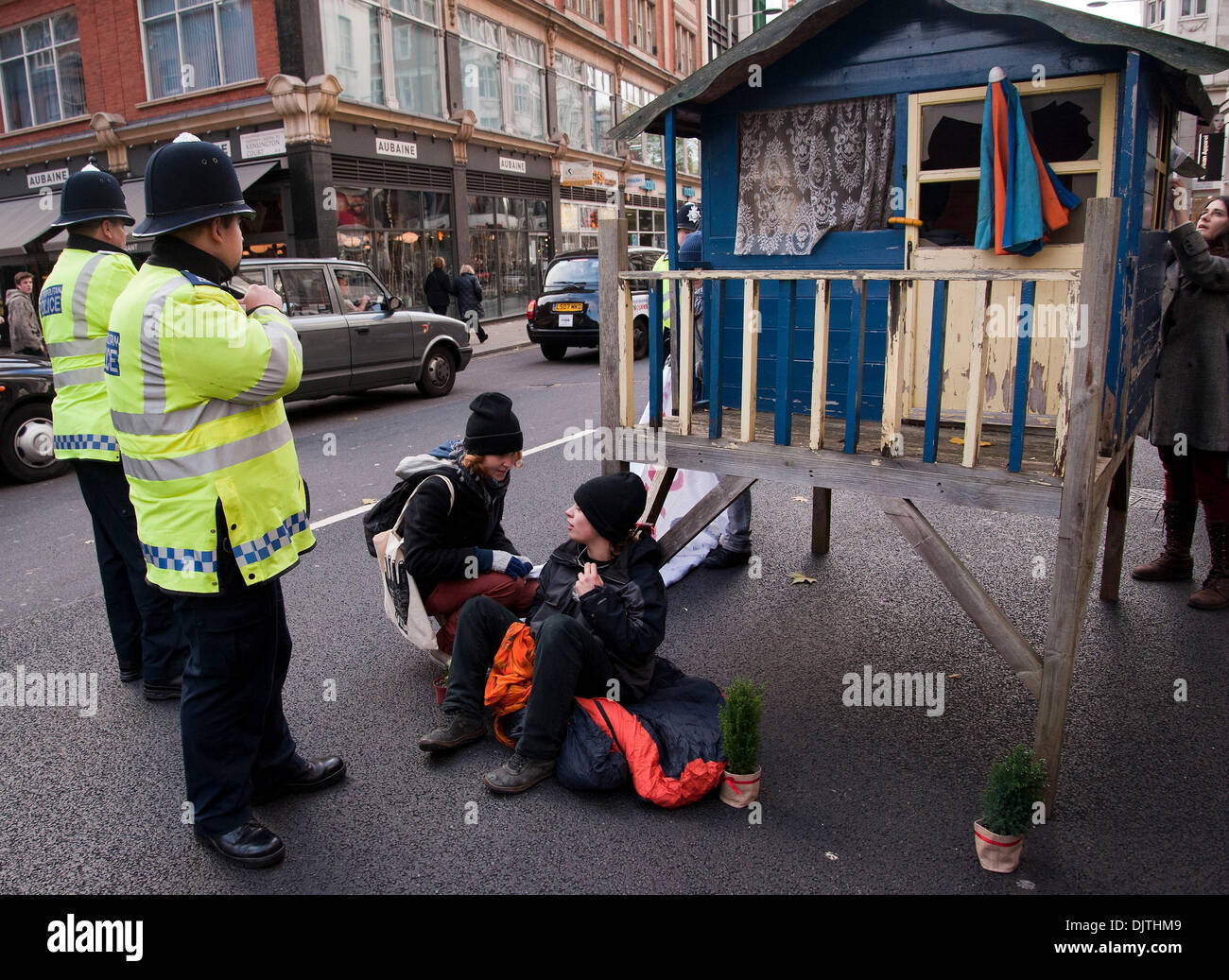 London, UK. 30th November 2013.Protesters against the proposed Israeli Prawer Plan block the road outside the Israeli Embassy with a small wooden house.Activists have 'locked on' to the structure with bike locks around their necks. The protesters claim that the Israeli government plans to displace 70, 000 Bedouin Palestinains to make room for Israeli settlements. Credit:  Pete Maclaine/Alamy Live News Stock Photo