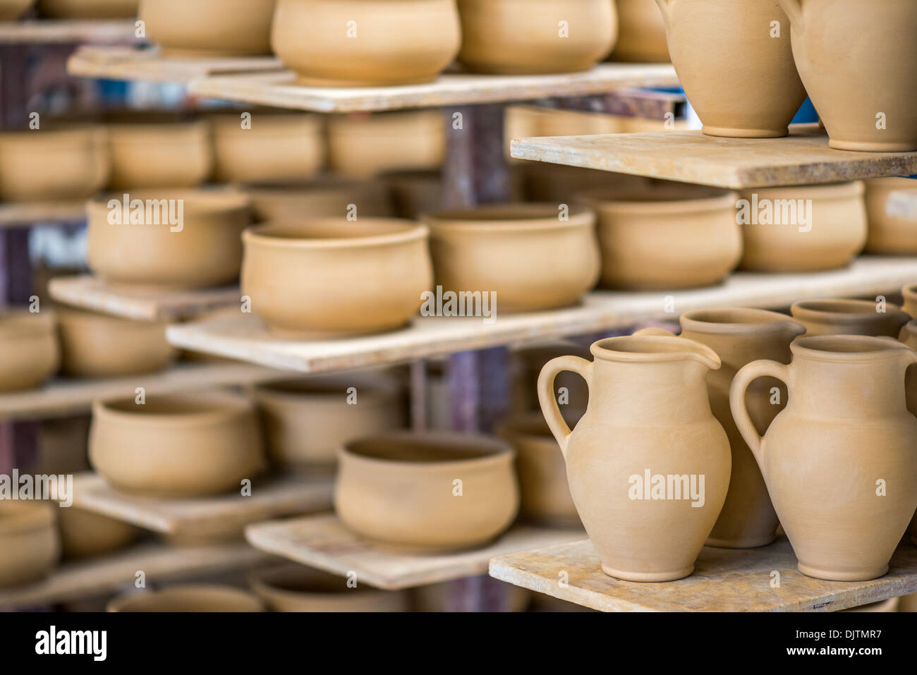 Shelves with ceramic dishware in pottery workshop Stock Photo