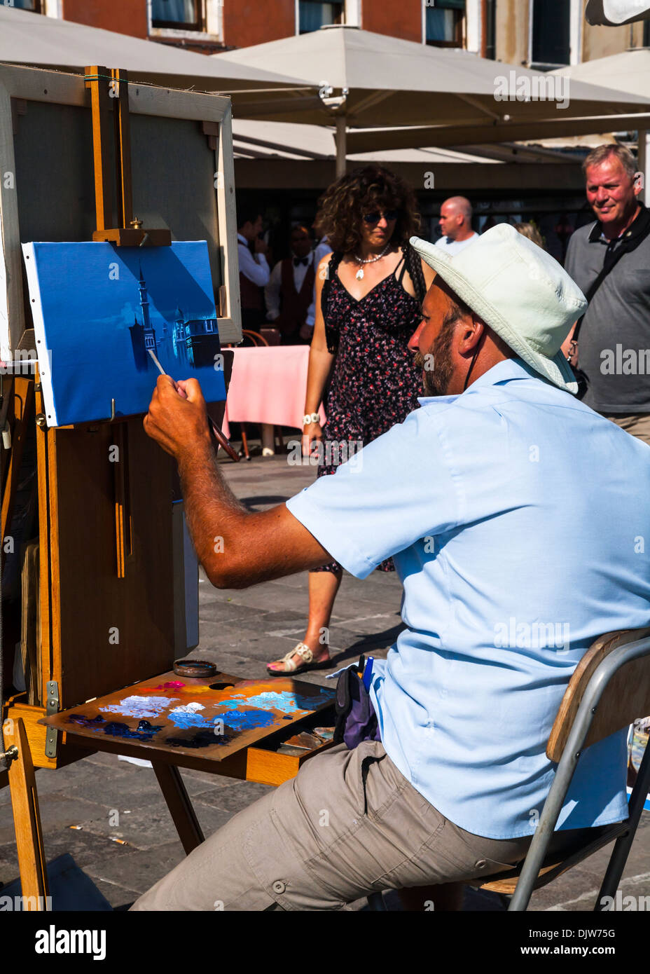 An artist at work on the streets of Venice painting a scene on canvas, Venice, Veneto, Italy. Stock Photo