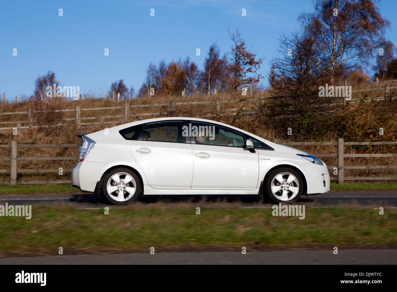 White Toyota Prius  full hybrid electric mid-size hatchback side view driving on uk road Stock Photo