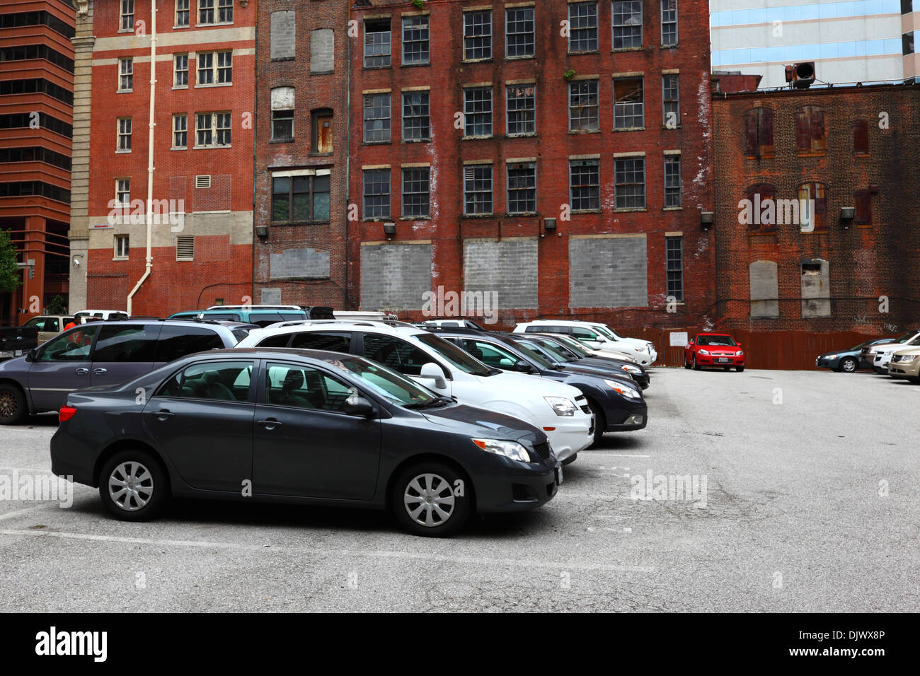 New cars in car park in front of abandoned old brick buildings in