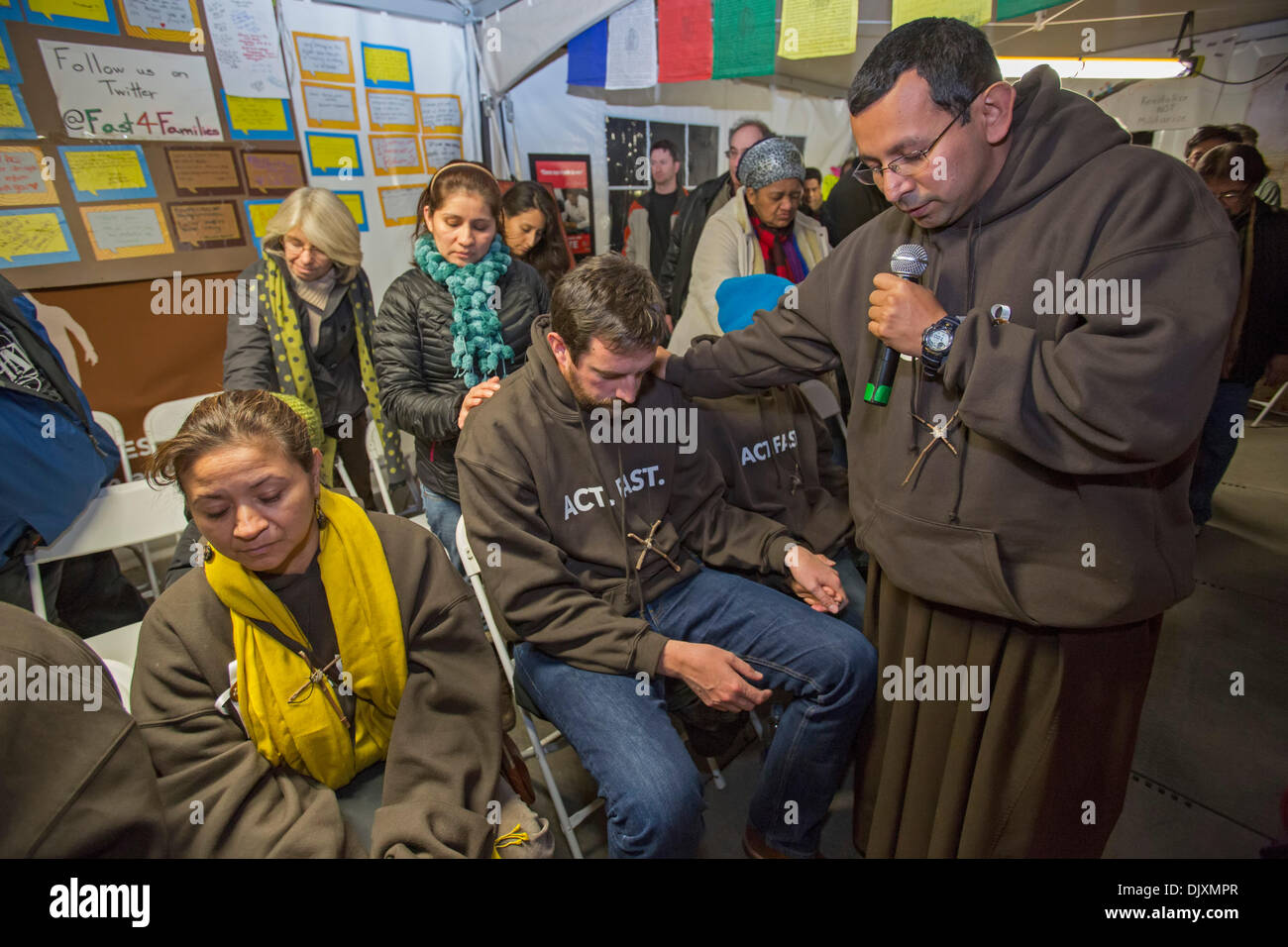 Washington, DC, USA. Immigration reform activists participate in a Fast for Families, a hunger strike aimed at pressuring the U.S. House of Representatives to vote on immigration reform legislation. The hunger strikers are in a tent on the Mall near the U.S. capitol. Brother Juan Turios of the Franciscan Action Network prays with the hunger strikers. Credit:  Jim West/Alamy Live News Stock Photo