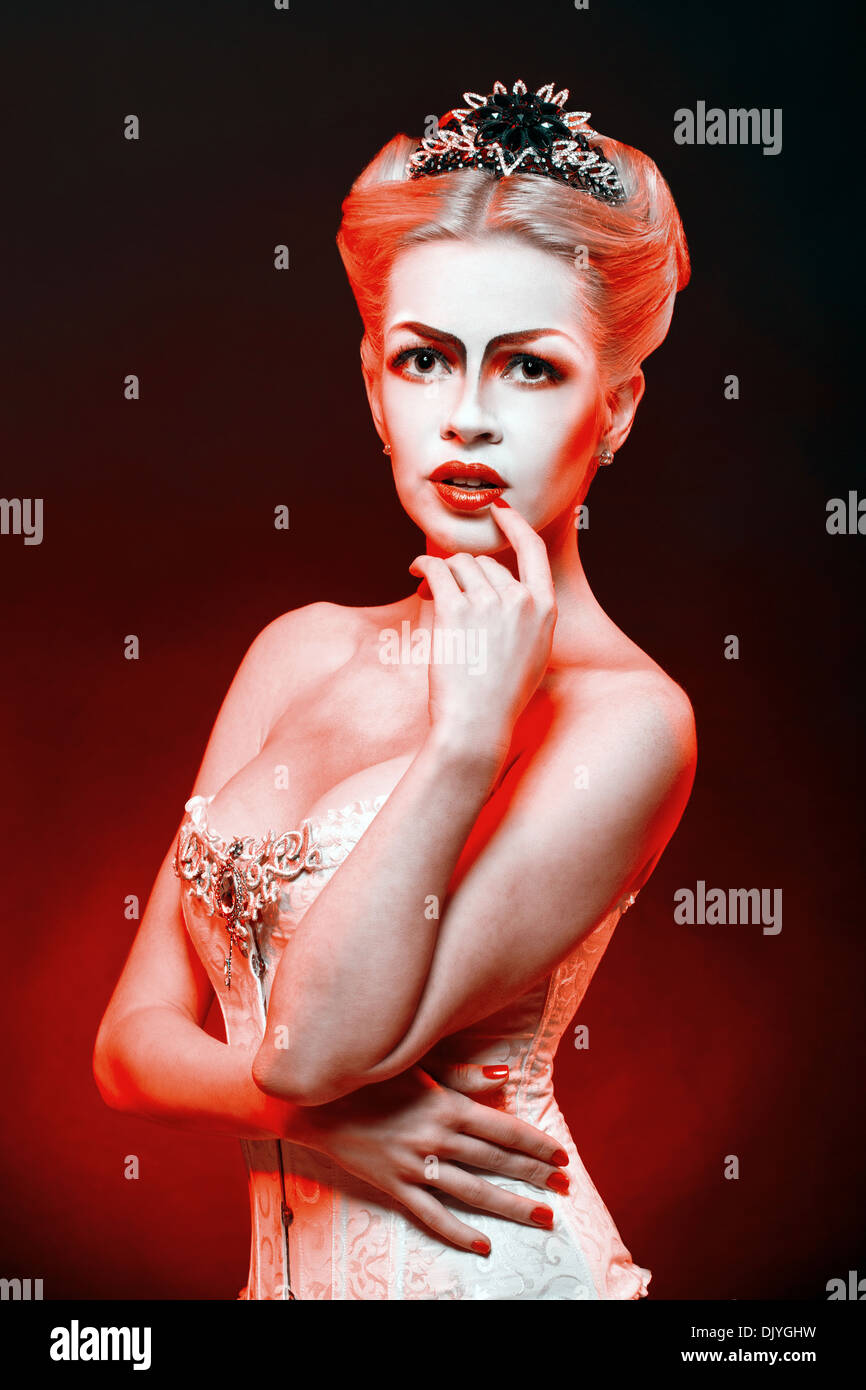 Red Queen with a crown and a corset, with makeup in studio shot Stock