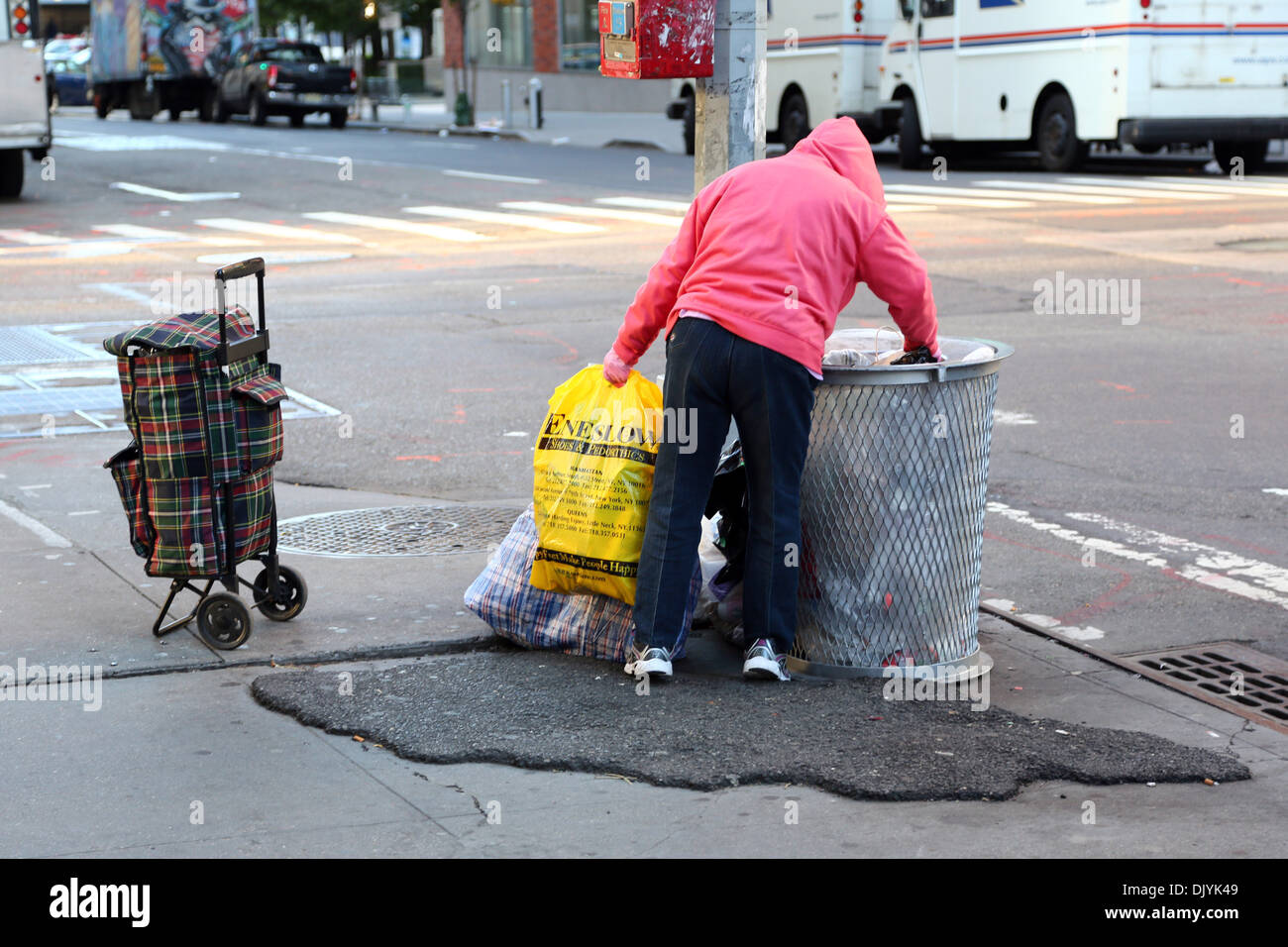 Homeless person looking through rubbish bins in the street in New York