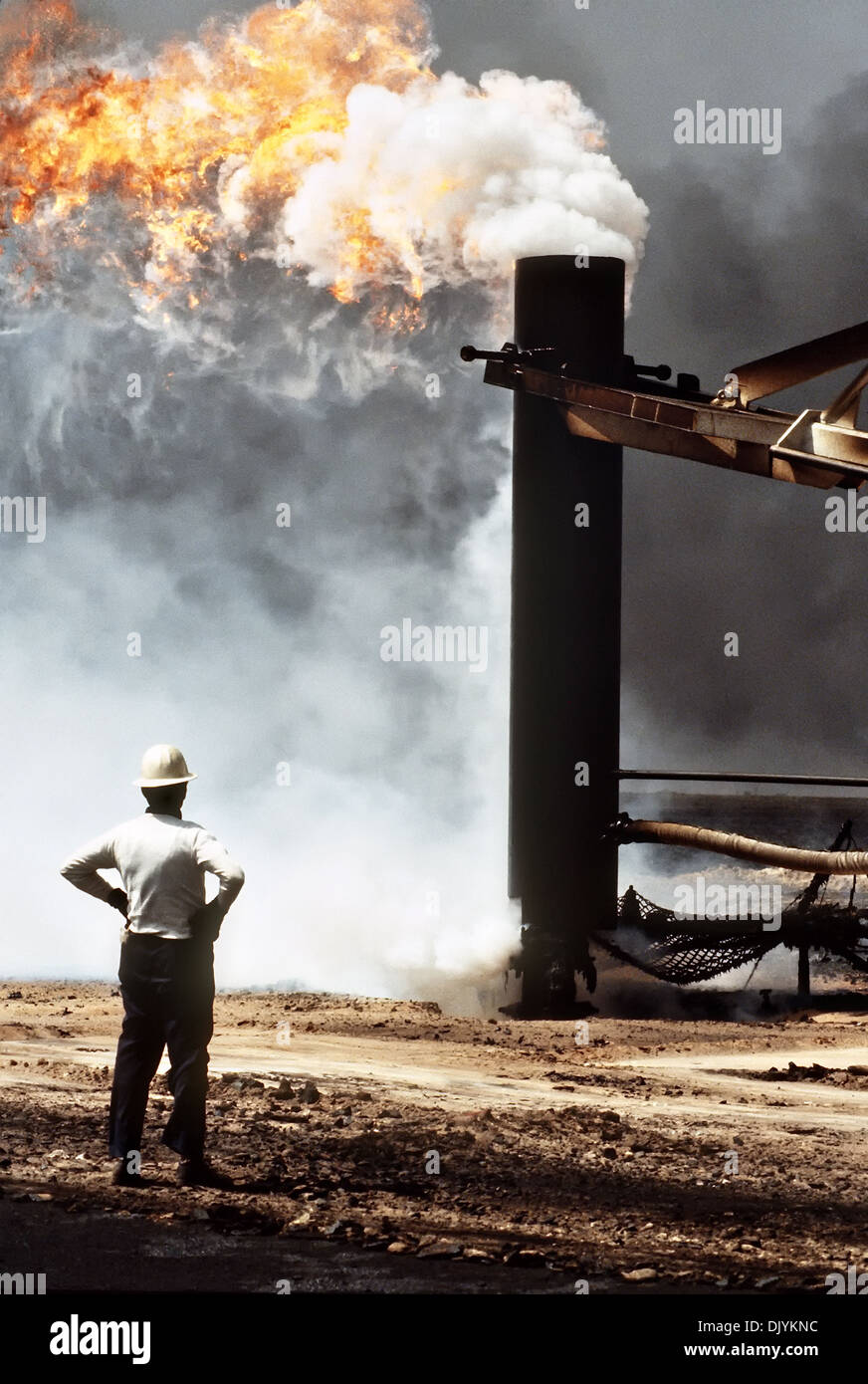Firefighters from the Boots and Coots Oil Well Firefighting Company use a crane to cap a blazing oil well in the aftermath of Operation Desert Storm April 7, 1991 in the Ahman Oil Fields, Kuwait. The well, situated in the Ahman Oil Fields, is one of many set afire by Iraqi forces prior to their retreat from Kuwait. Stock Photo