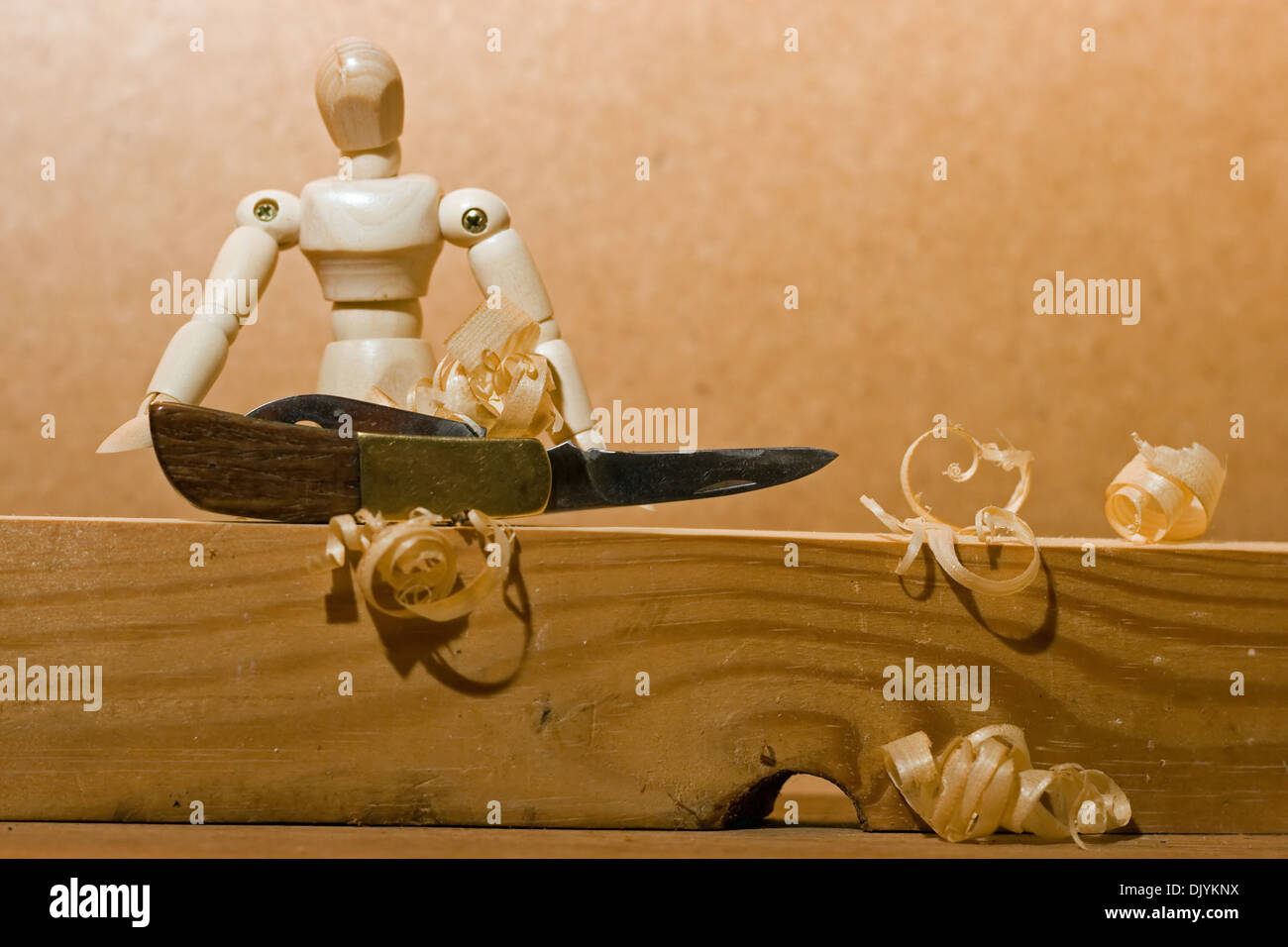 Manikin with penknife and wood shavings. Stock Photo
