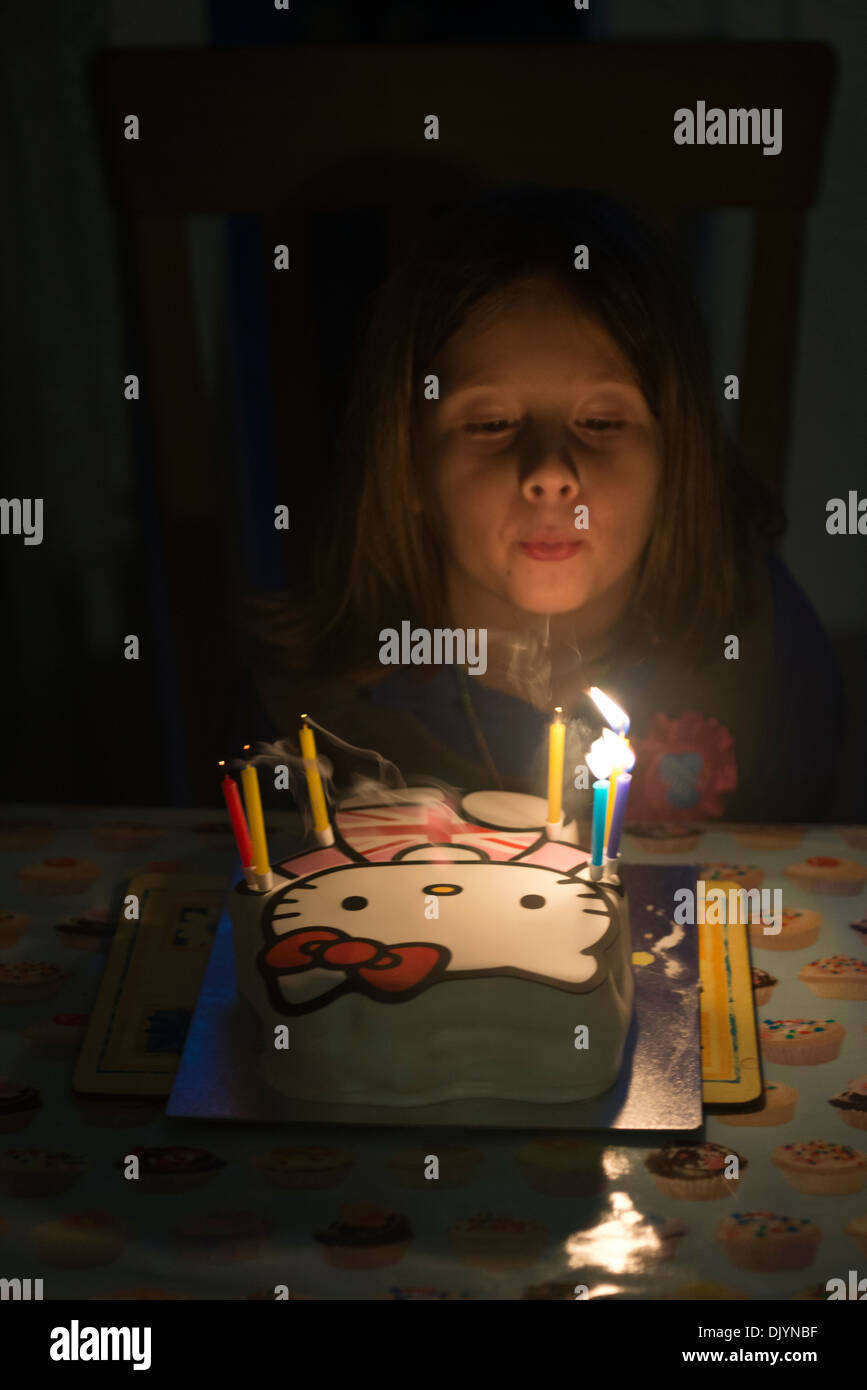 A young girl celebrates her birthday by blowing out the candles on her birthday cake. Stock Photo