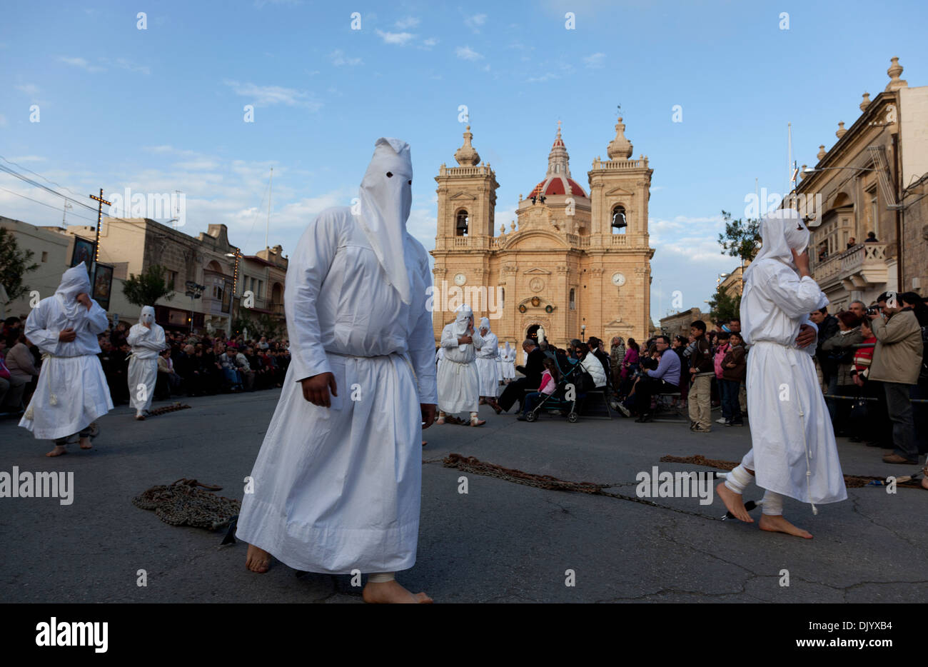 Robed and hooded penitents drag bundles of chains throughout the streets during Good Firday in Malta as a form of penance.  Stock Photo