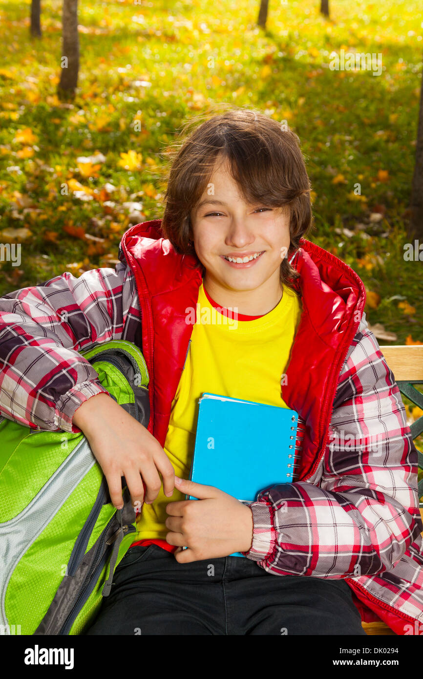 Close portrait of 12 years old boy after school smiling and sitting in park Stock Photo