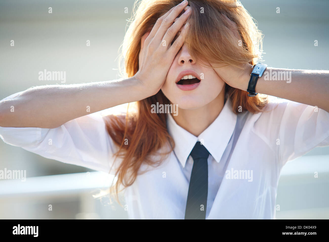 Delightful young woman closed her eyes with both hands Stock Photo