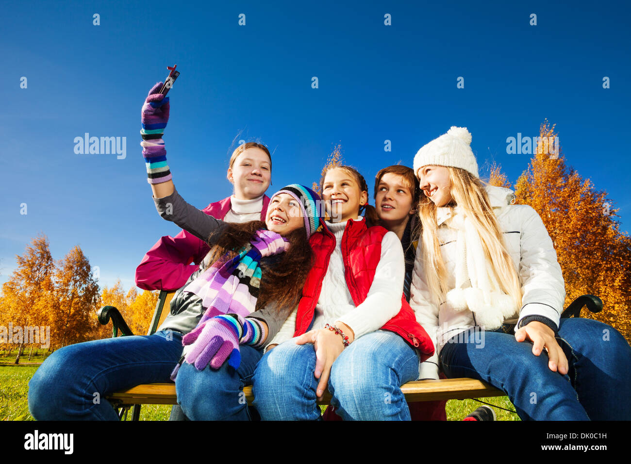 Kids, teen boy and girls photographing themselves with camera on cell phone hugging smiling and posing Stock Photo