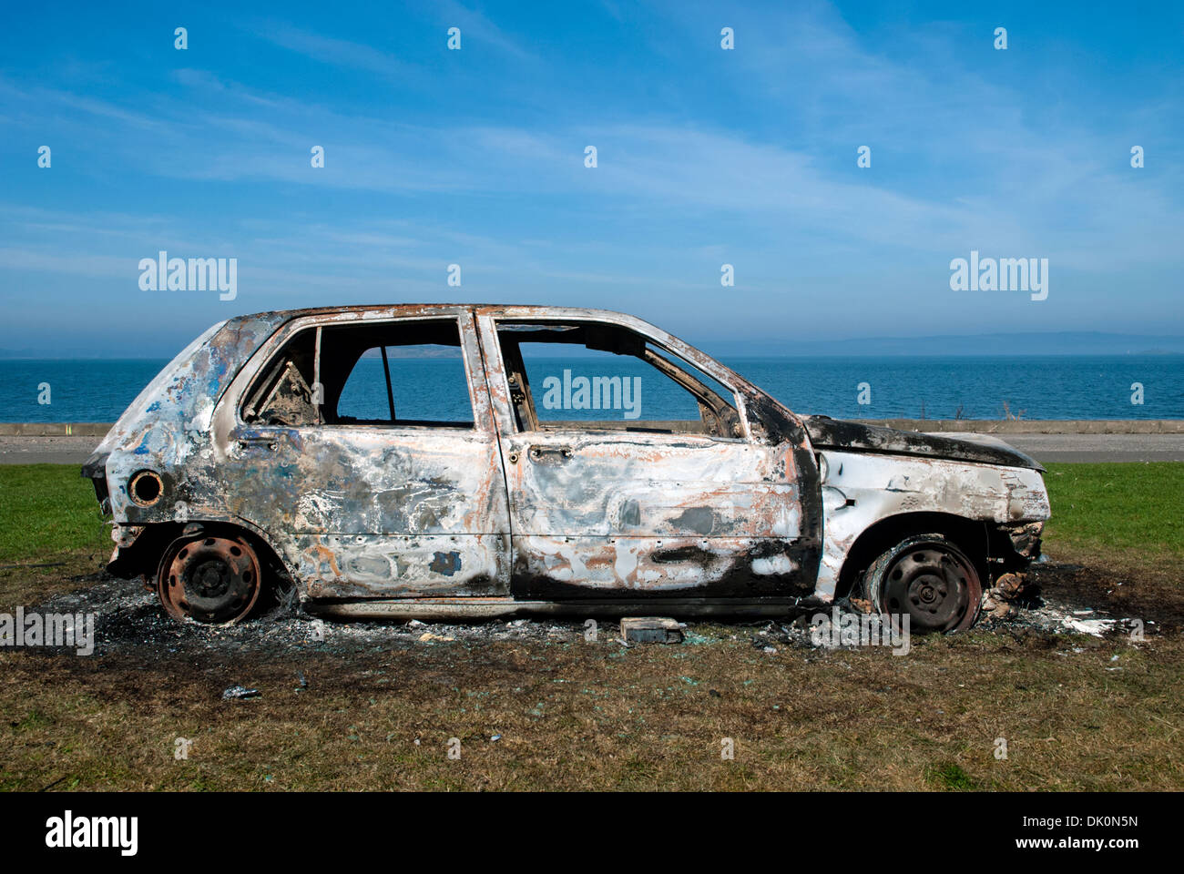 Stolen, abandoned and burnt out car on the foreshore at Granton, Edinburgh. Stock Photo