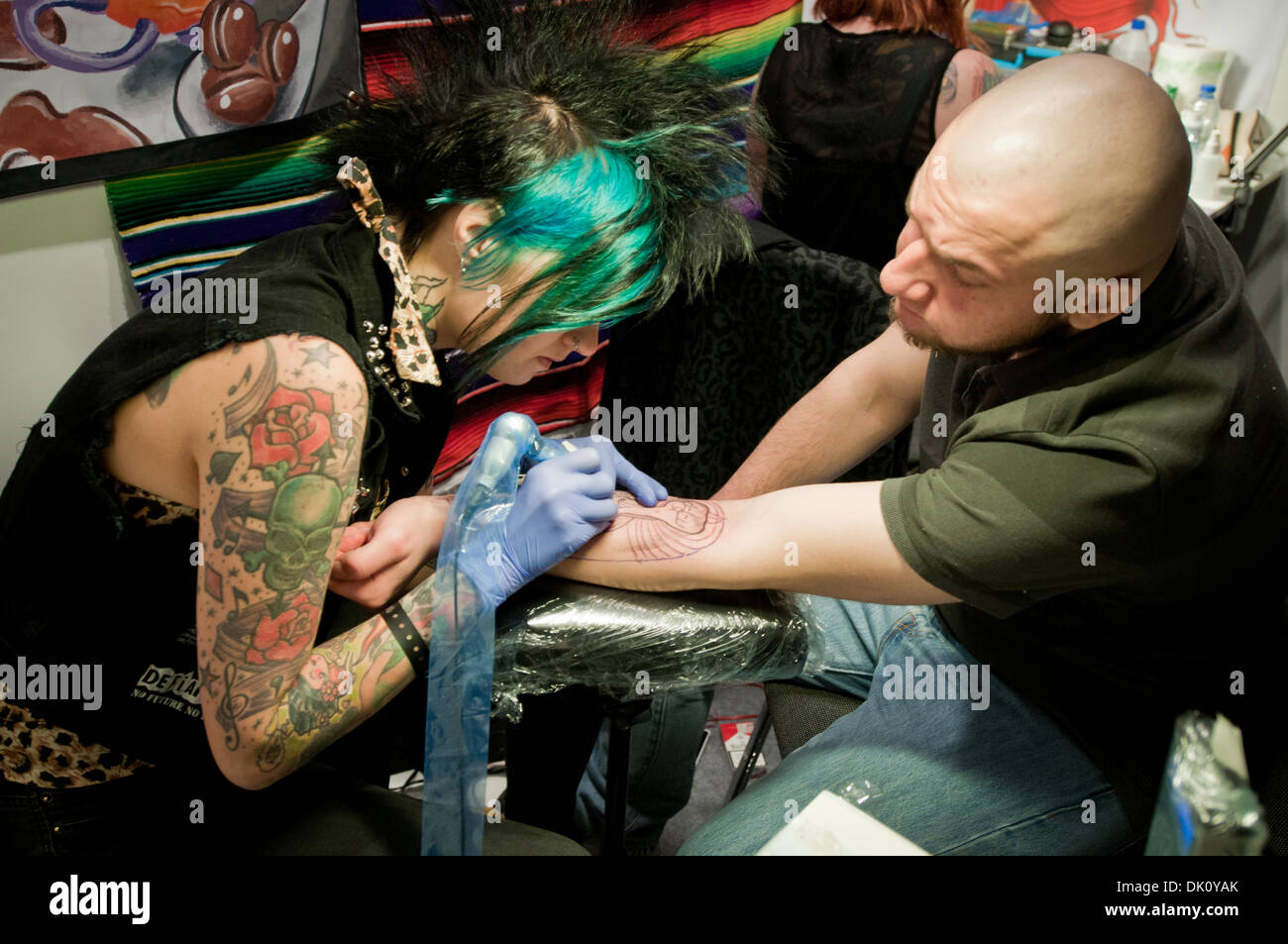 Warsaw, Poland. 1st December 2013. Female tattoo artists works with his client during the second day of tattoo, body painting and pierceing show - 1st Warsaw Tattoo Convention 2013 in Pepsi Arena in Warsaw, Poland Credit:  kpzfoto/Alamy Live News Stock Photo