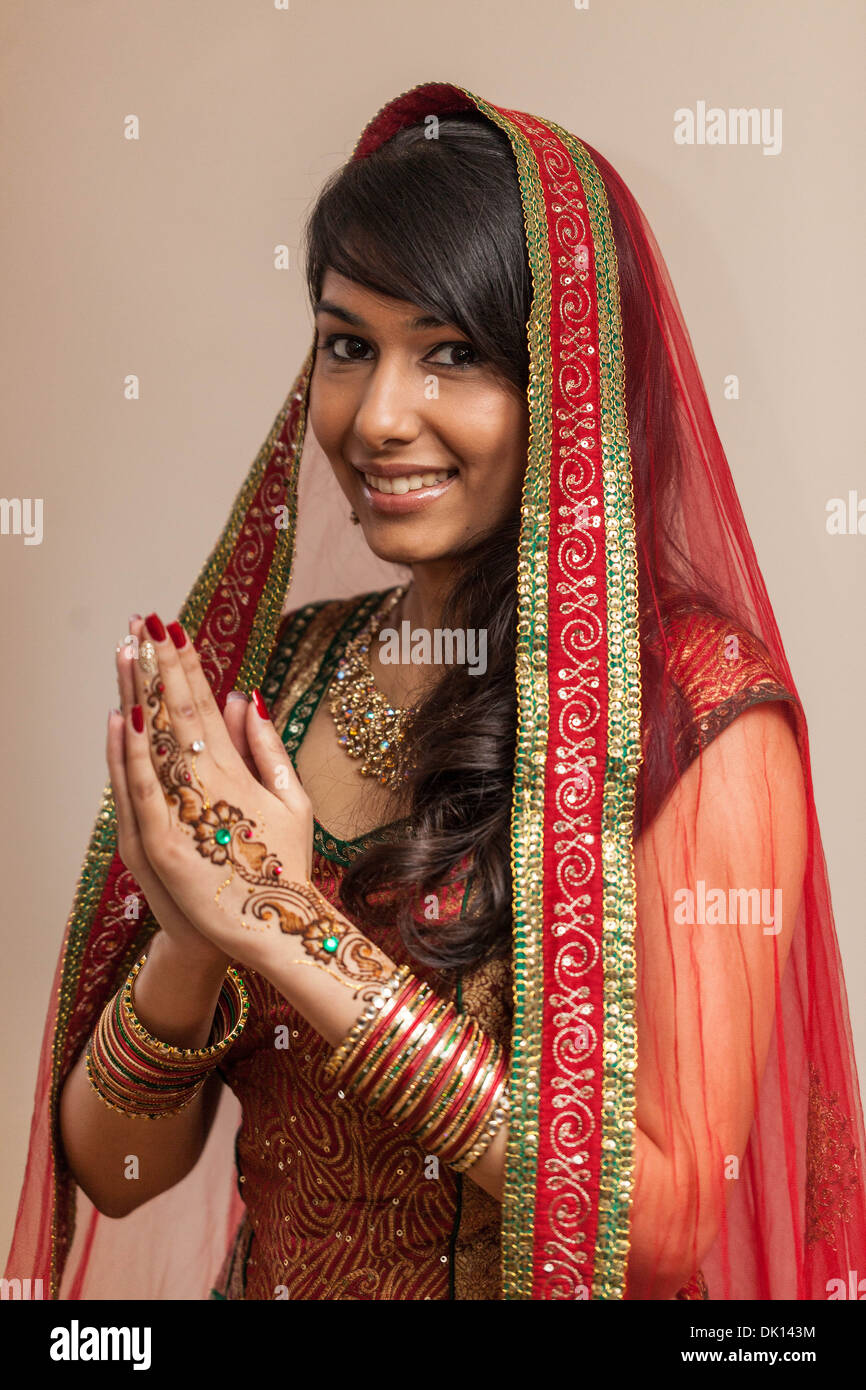 Portrait of an Indian woman dressed in traditional sāri and sporting henna tattoos on her hands, in a Namaste gesture. Stock Photo
