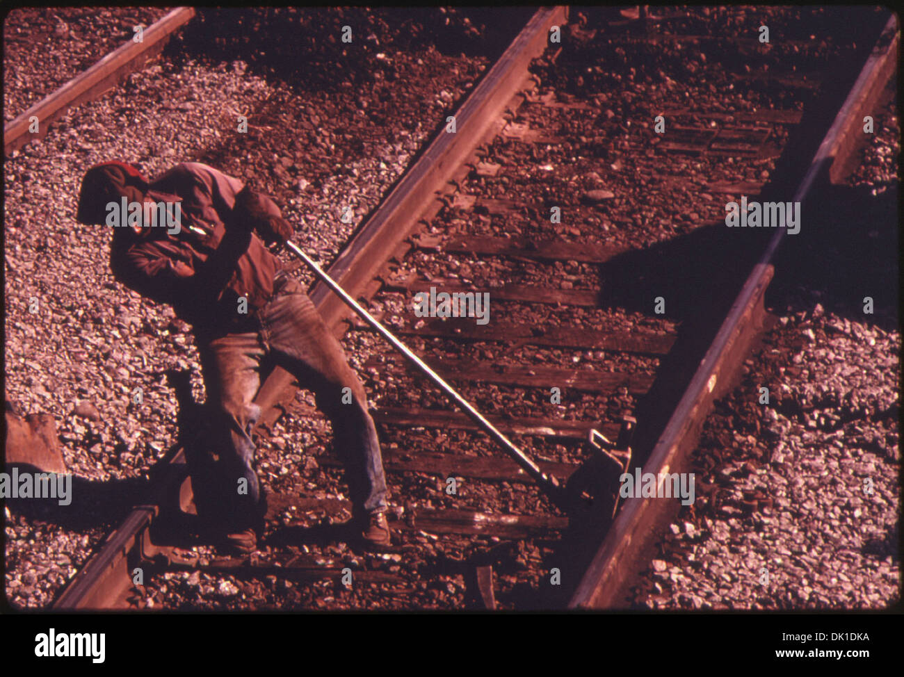 SOUTHERN RAILWAY RIGHT-OF-WAY WORKER JACKS UP A RAIL SO TIES CAN BE REPLACED. IN 1974 SOUTHERN SPENT 18.6 PERCENT OF... 556896 Stock Photo