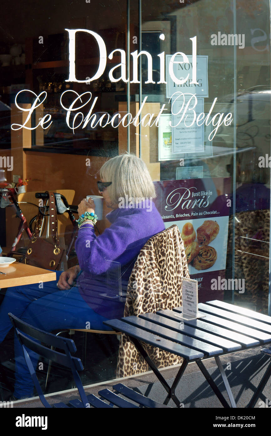 Elderly grey haired woman senior drinking coffee or mug of tea in the window of a cafe on south Granville Street in Vancouver, BC, Canada Stock Photo